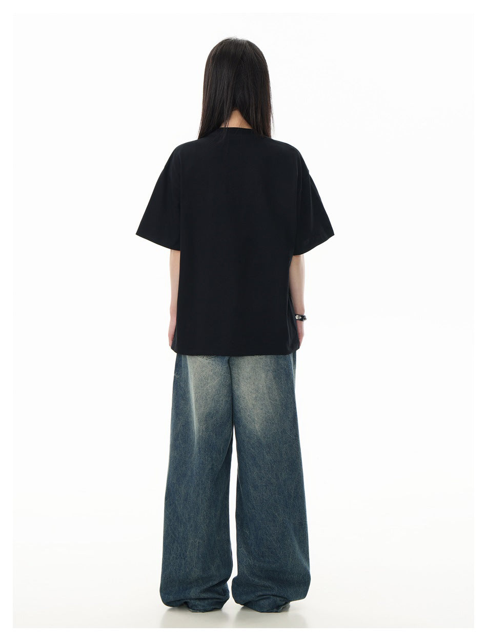 Back view of a model wearing a plain black short-sleeve T-shirt and loose blue jeans.
