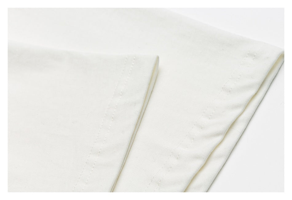 Close-up of a stitched hem and folded edge on off-white fabric.