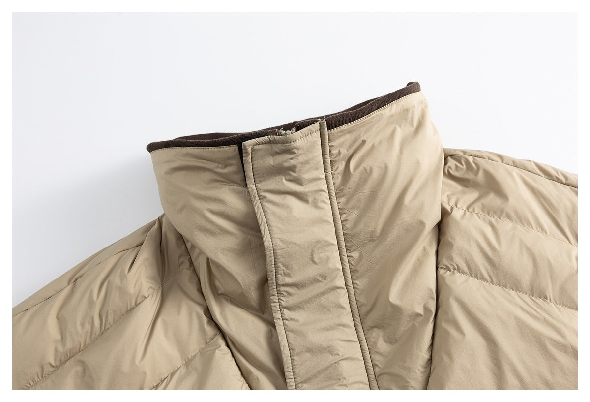 Close-up of a beige padded jacket's high collar and front fastening with dark brown trim.