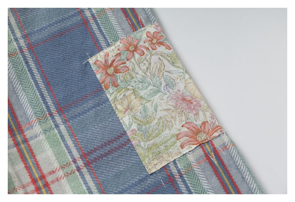 Close-up of a floral-print fabric pocket detail against a blue plaid shirt.
