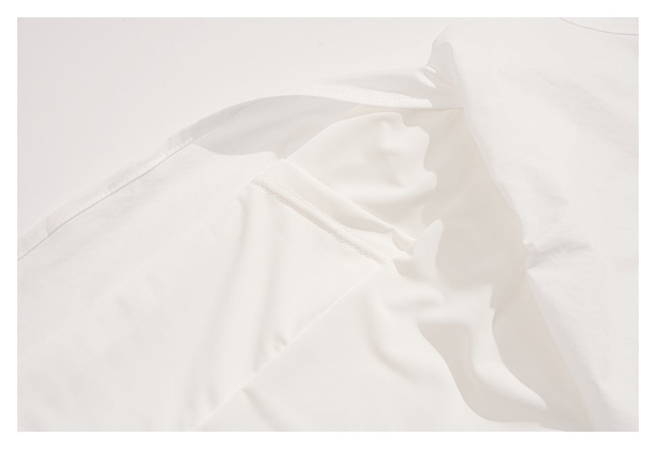 Close-up of white garment interior with overlapping fabric, folds, and stitched seams.