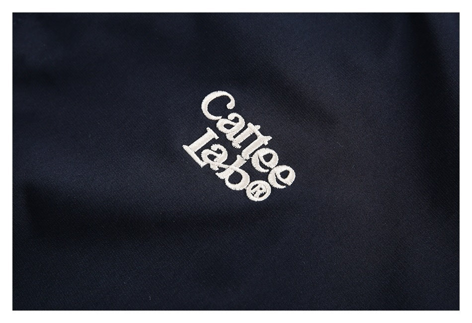 Close-up of white embroidered lettering on navy jacket fabric.