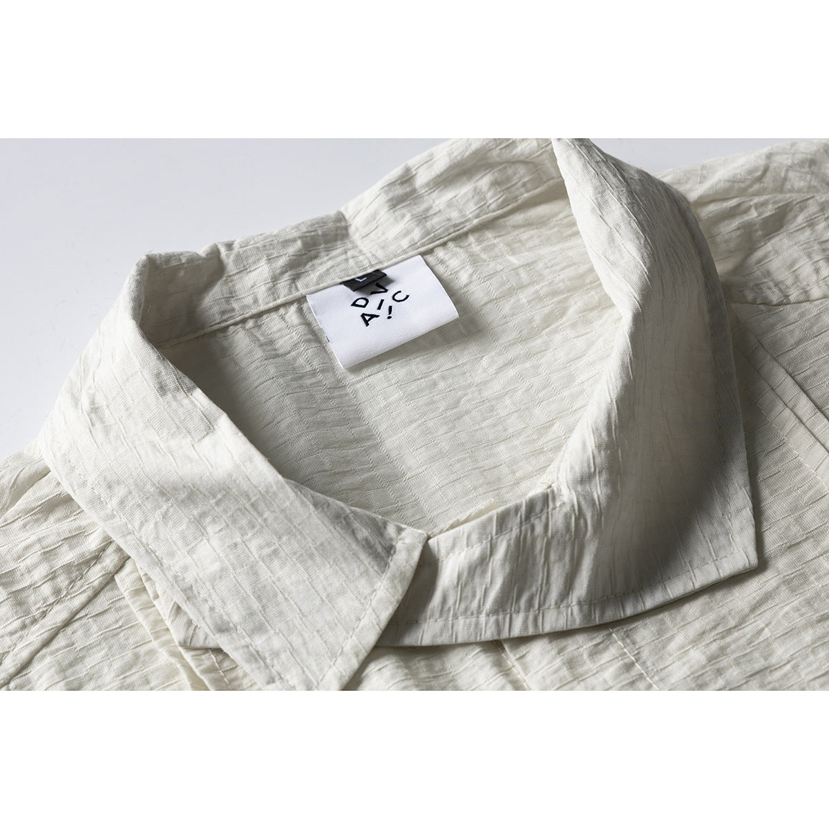 Close-up of an off-white shirt's wide collar and attached neck label.