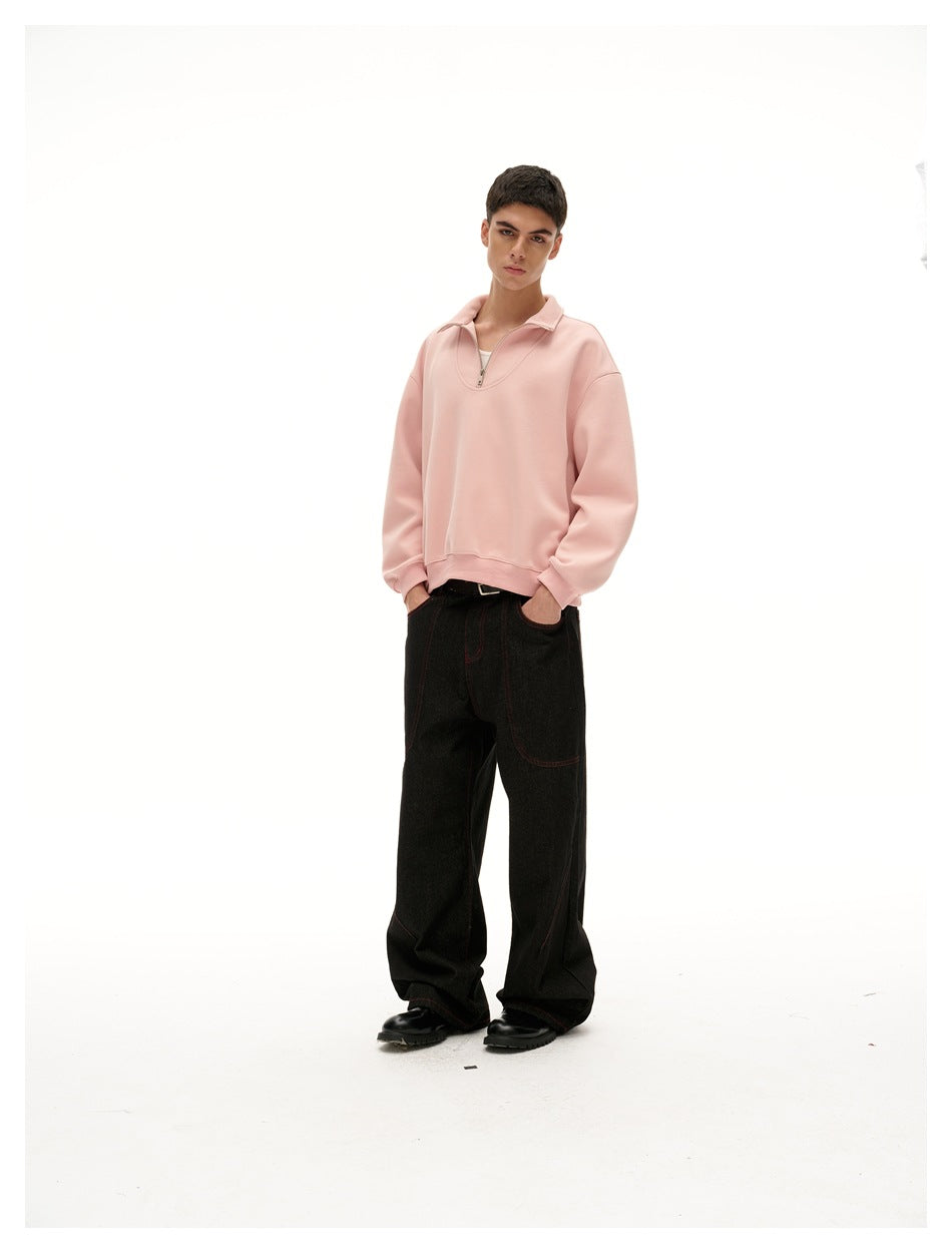 Three-quarter front view of a model wearing a pale pink quarter-zip pullover and loose black jeans.