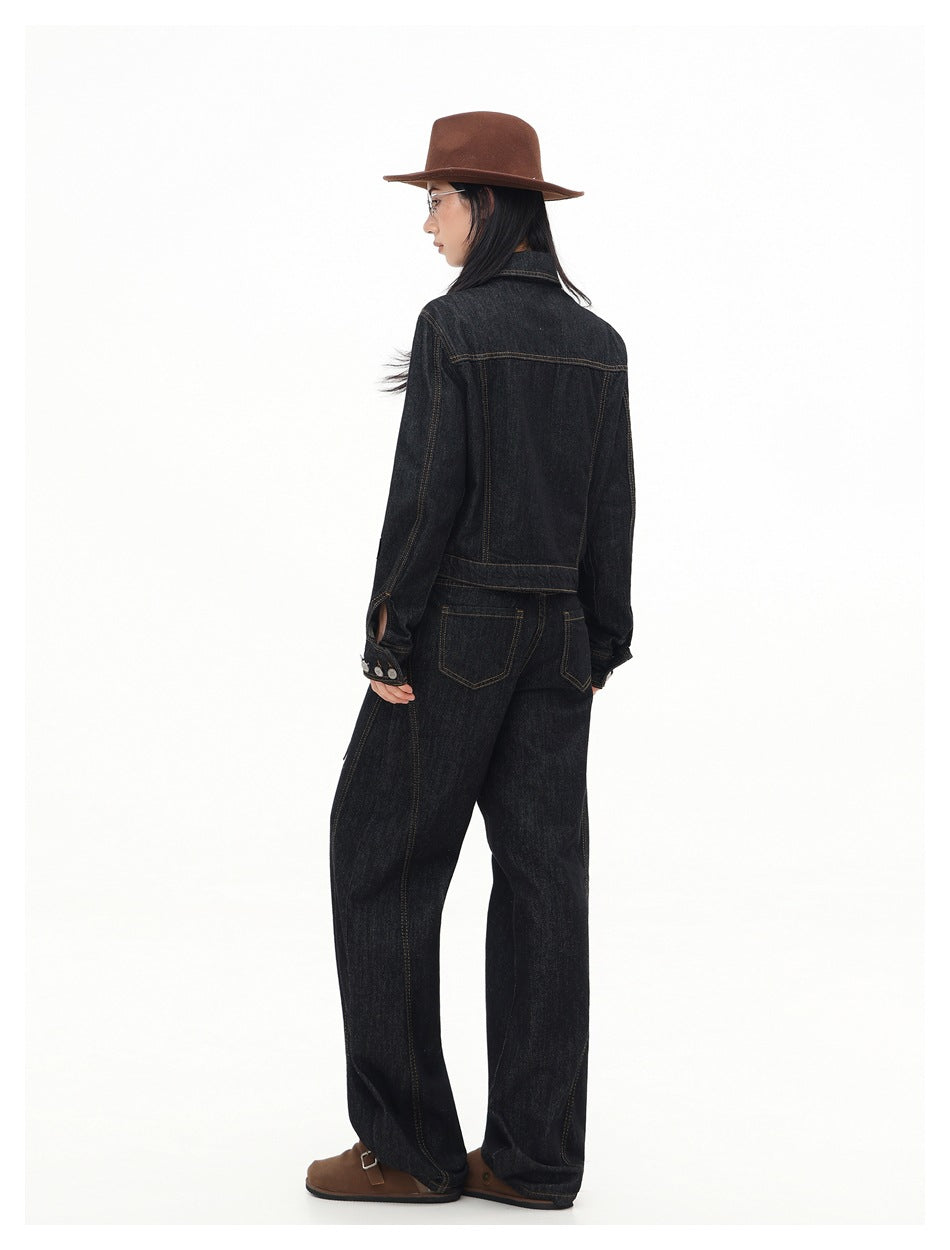 Model shown from behind in a dark indigo denim jacket and matching wide-leg jeans, with contrast stitching and back pockets.