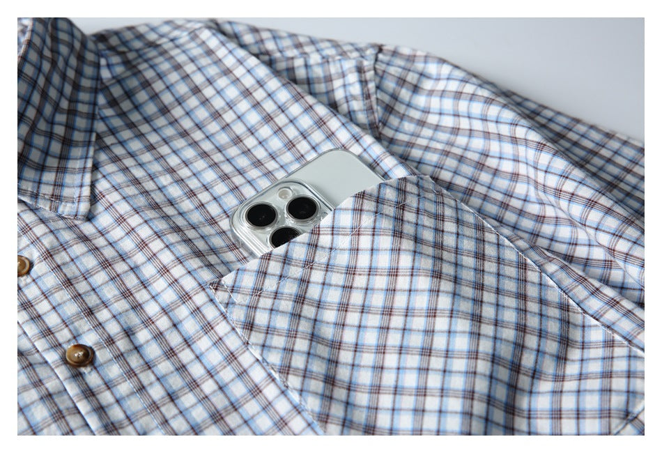 Close-up of a blue-and-brown plaid shirt pocket holding a silver smartphone.