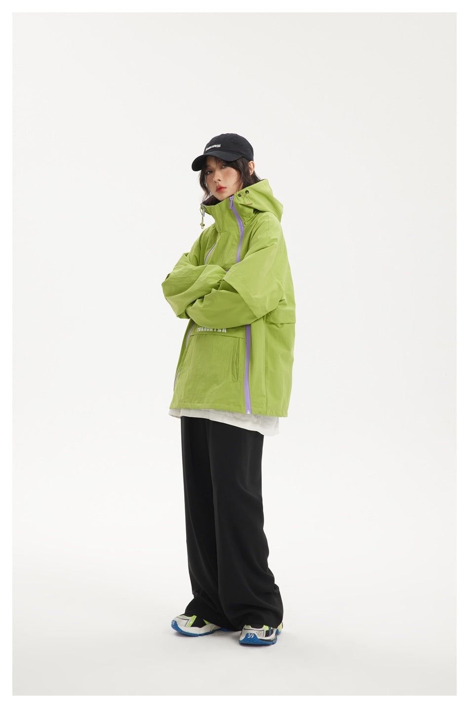 Side view of a model wearing a lime green hooded jacket with lavender zippers and black pants.