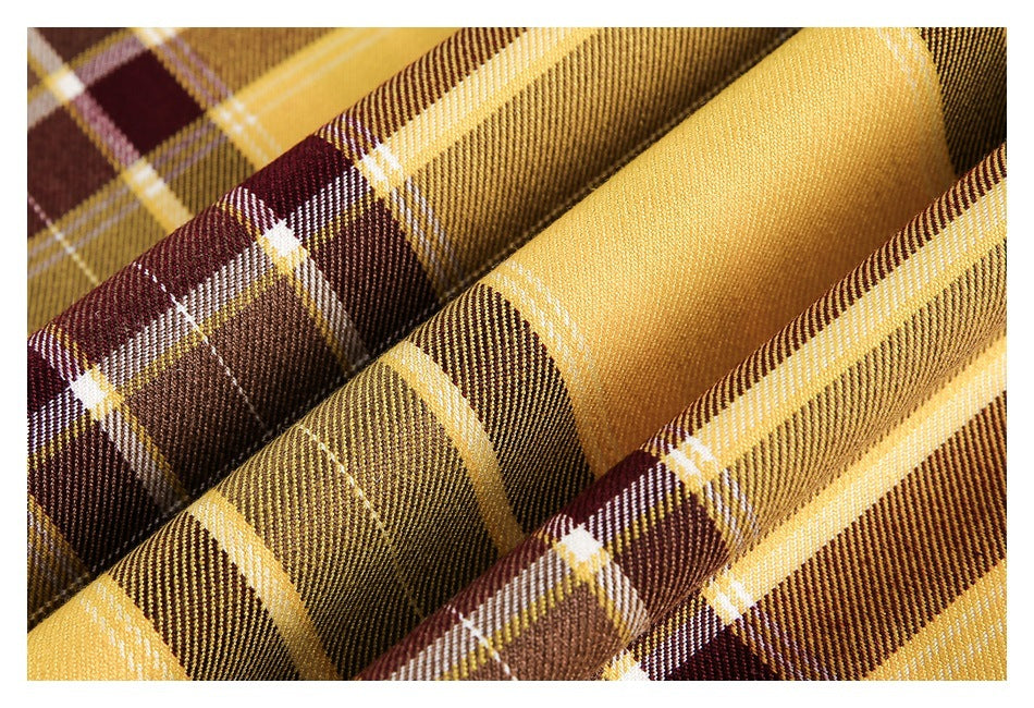 Macro view of mustard, brown and burgundy plaid fabric, showing its woven pattern and stitching.