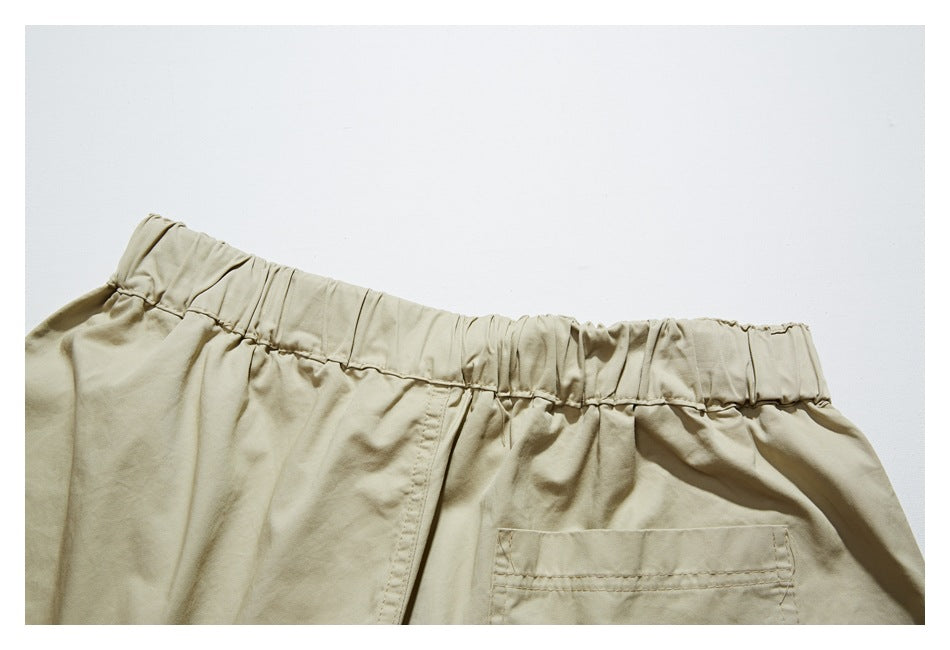 Close-up of the back waist and pocket area of beige trousers with an elastic waistband.