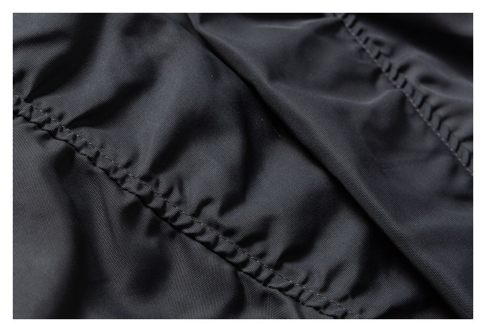 Close-up of stitched seams on dark charcoal garment fabric.