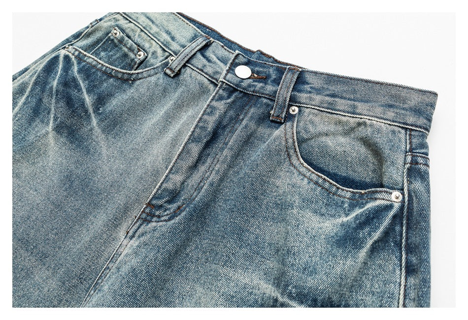 Close-up of the front waistband and pocket area of faded blue jeans, with a button and metal rivets.