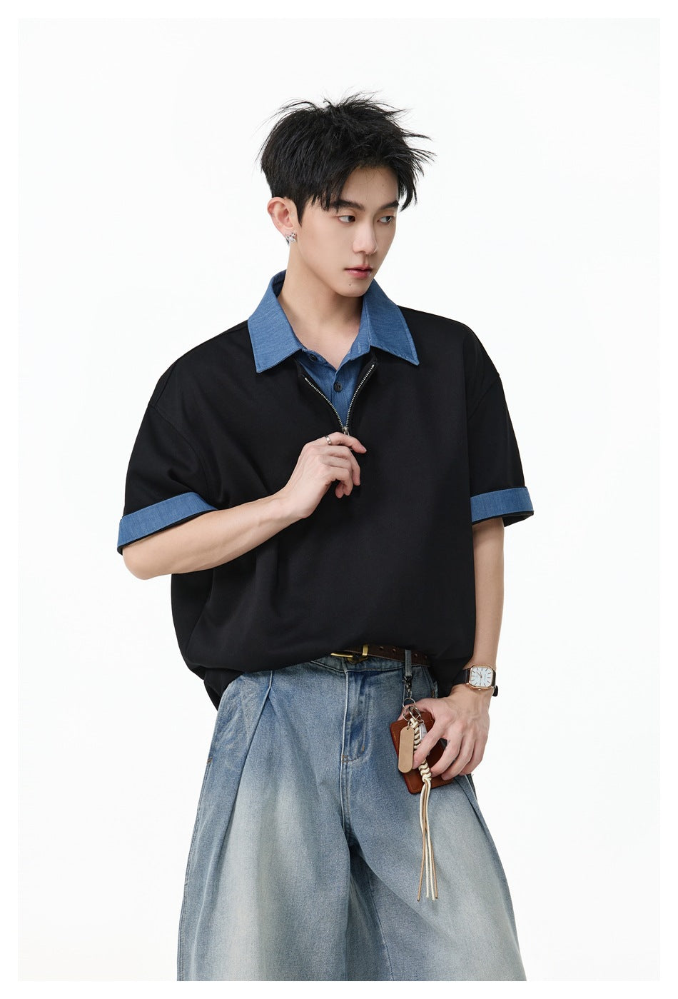 Closer view of a model wearing a black quarter-zip polo with a blue collar and sleeve cuffs, paired with light-wash jeans.