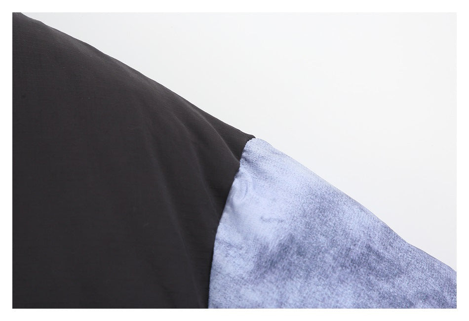 Close-up of the jacket's black and mottled blue-gray panels meeting at a diagonal seam.