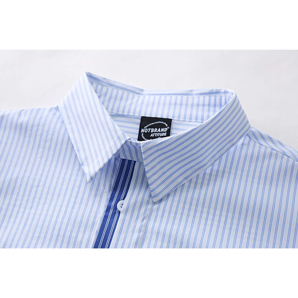 Close-up of a white shirt collar with fine blue stripes and a dark blue striped placket.