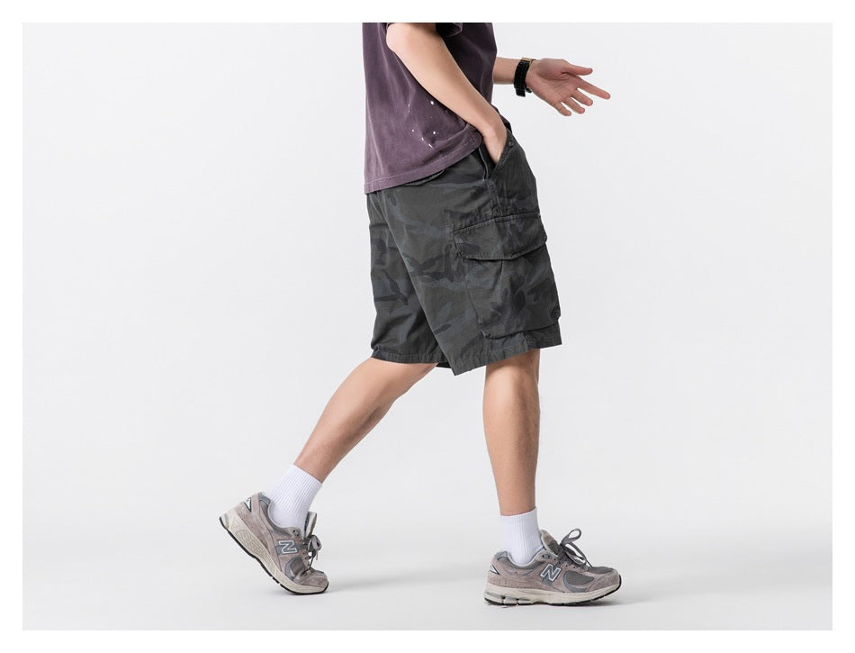 Side view of a model wearing dark charcoal camouflage cargo shorts with a large flap pocket.