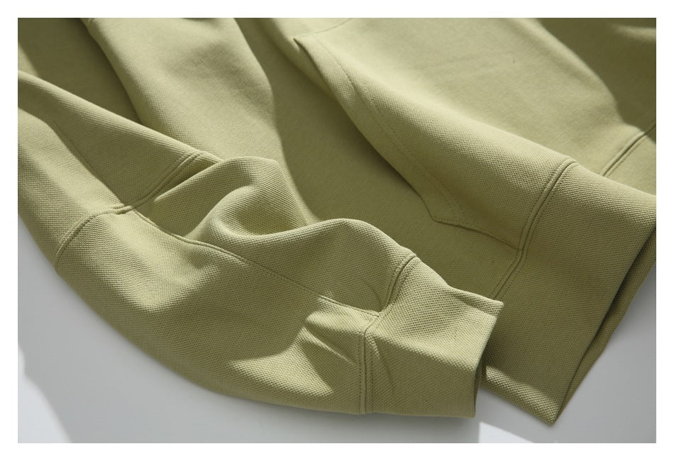 Close-up of the muted olive hoodie’s sleeve, ribbed cuff, and stitching, laid flat.