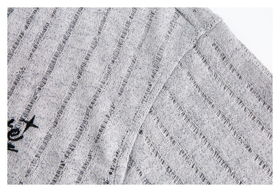Close-up of a gray top showing its shoulder seam and openwork stripe texture.