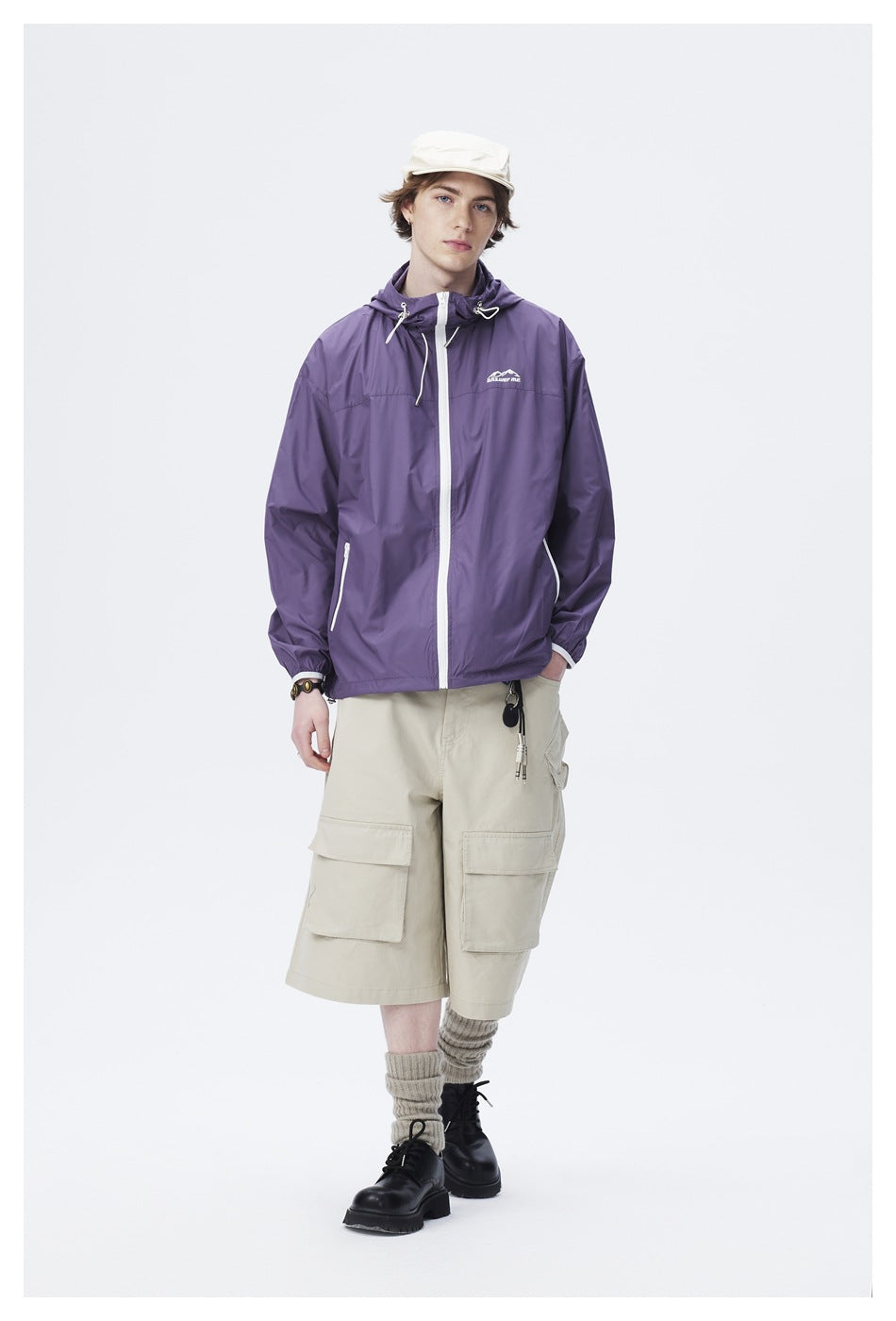 Model wearing a purple hooded jacket with white zippers and beige cargo shorts.