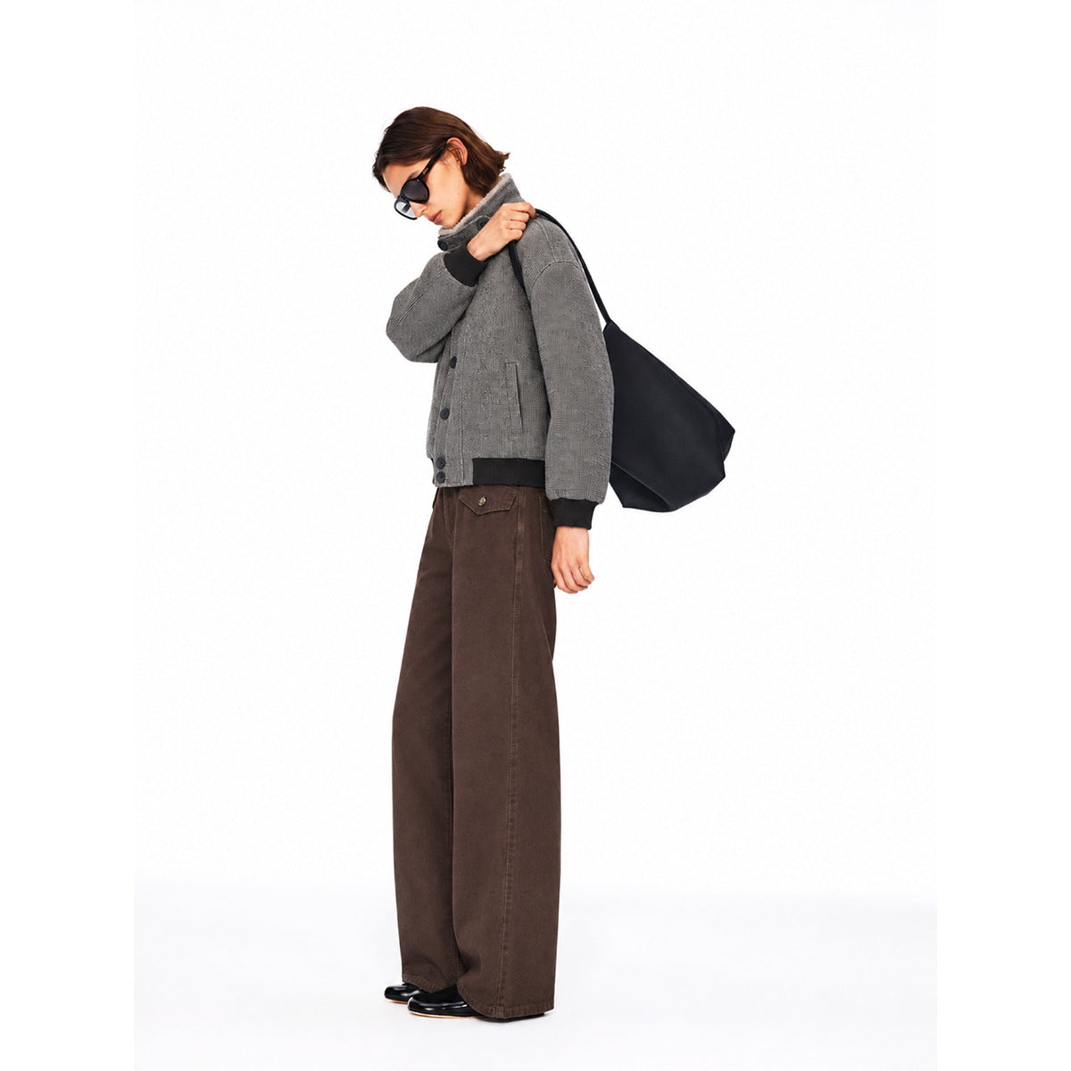 Side view of a model wearing a gray button-front jacket and wide-leg brown pants.