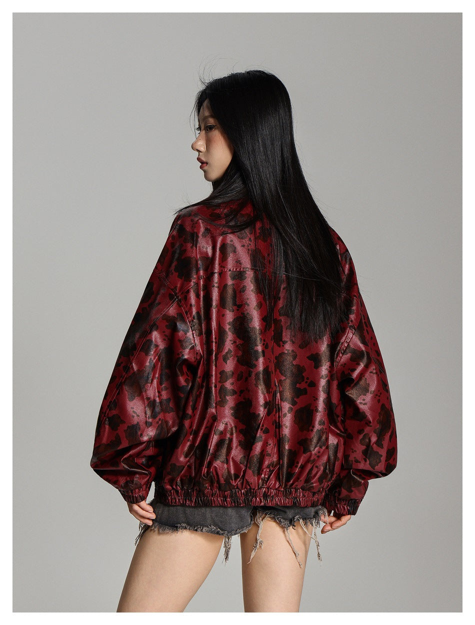 Model showing the back of a glossy burgundy jacket with an irregular black print and elastic hem and cuffs.