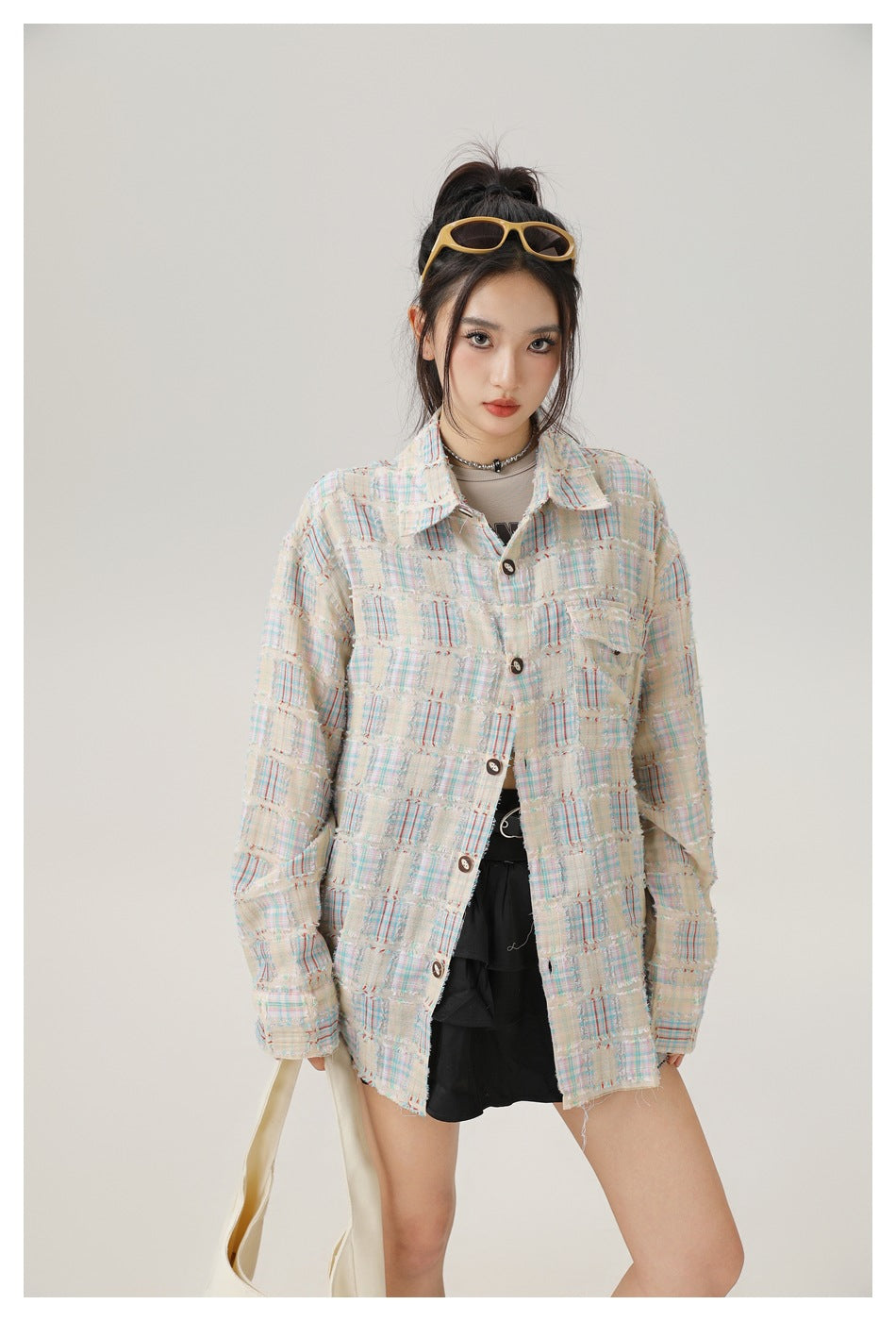 Model in a cream pastel-plaid oversized button-front shirt with a chest pocket and frayed edges.