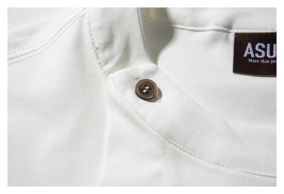 Close-up of the white shirt’s neckline seam and brown button, with part of the neck label visible.