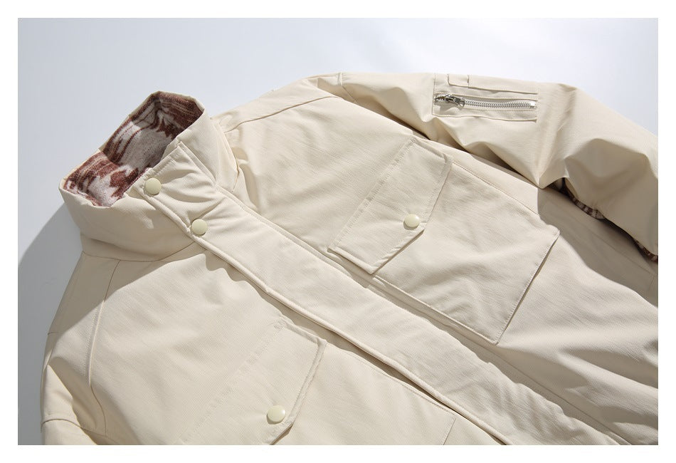 Close-up of an ivory jacket with a high collar, snap buttons, flap pockets and a patterned inner lining.