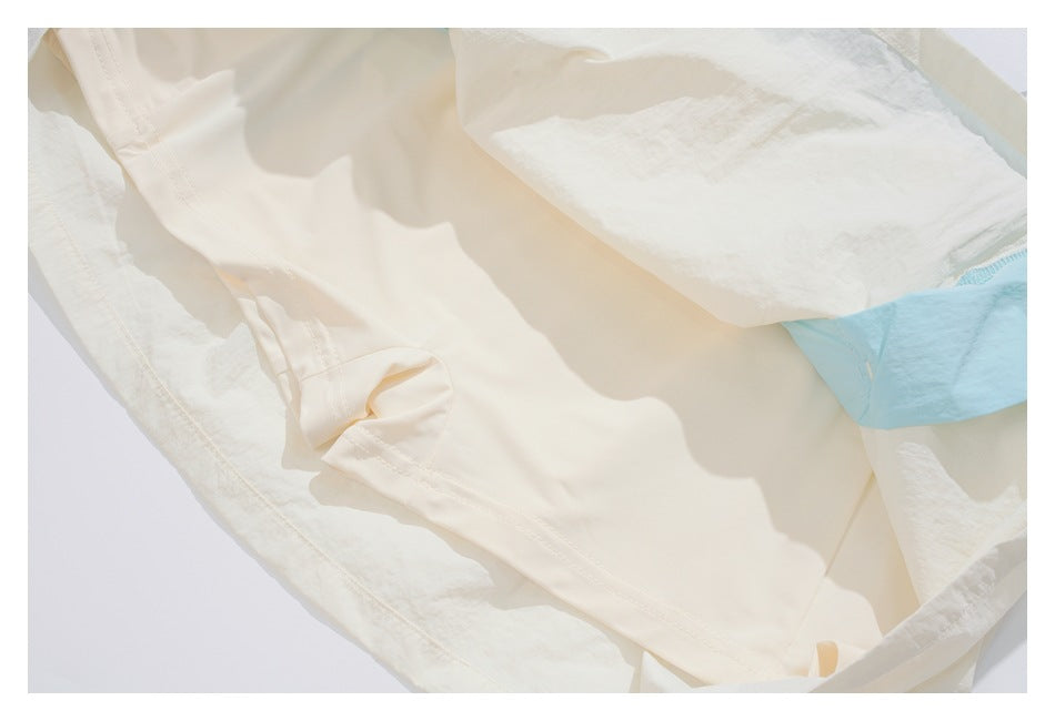Inside view of the cream garment showing smooth lining, stitched seams, and a pale blue fabric section.
