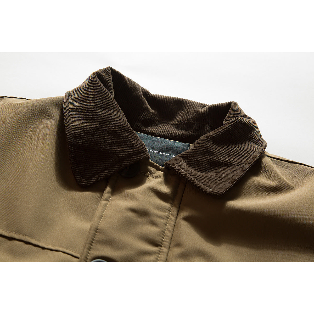 Close-up of a tan jacket with a dark brown ribbed collar and button-front placket.