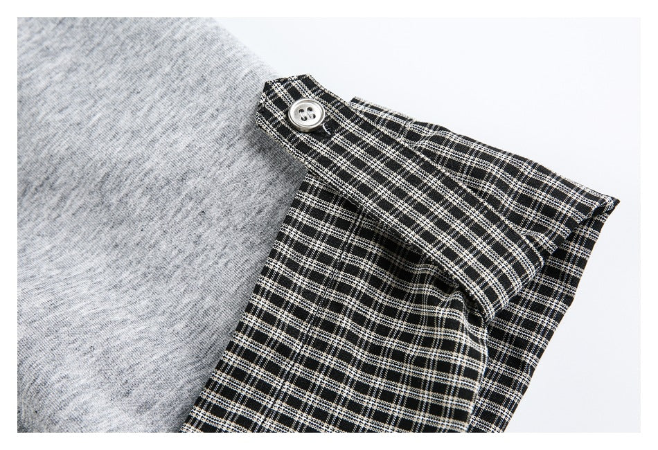 Close-up of a black-and-white checked cuff with a button on a gray top.