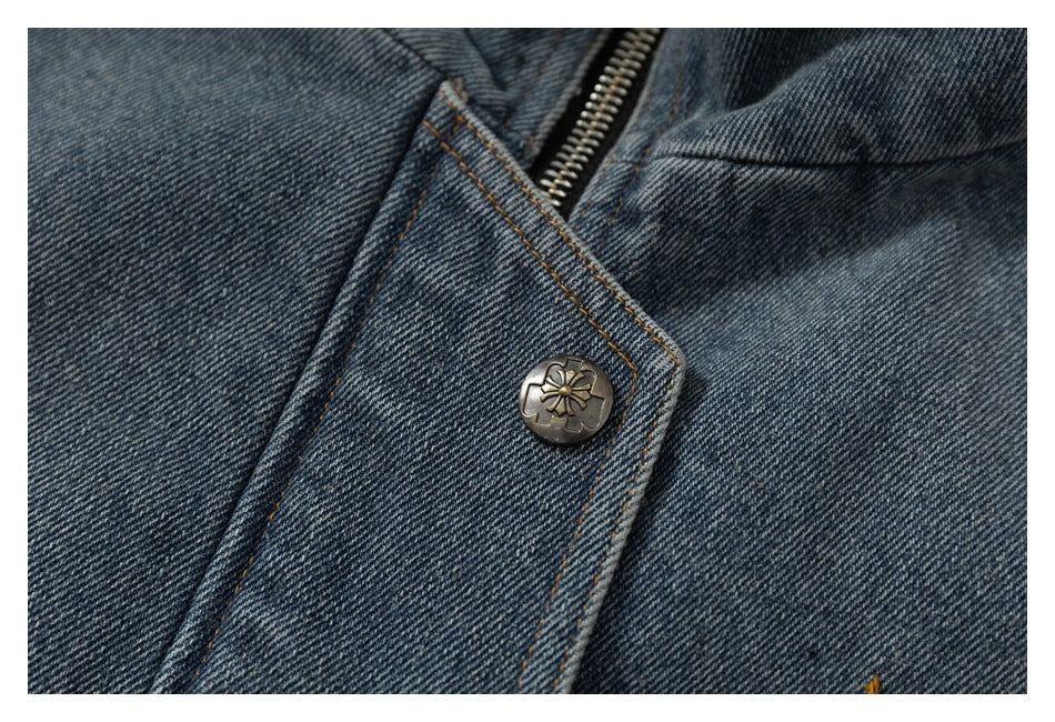 Close-up of blue denim fabric, orange stitching, a metal zipper, and a decorative flower-motif snap.