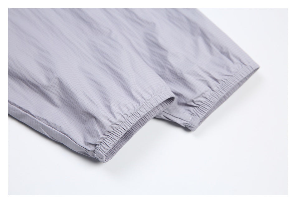 Close-up of two elasticized garment openings in pale gray fabric with a fine grid pattern.