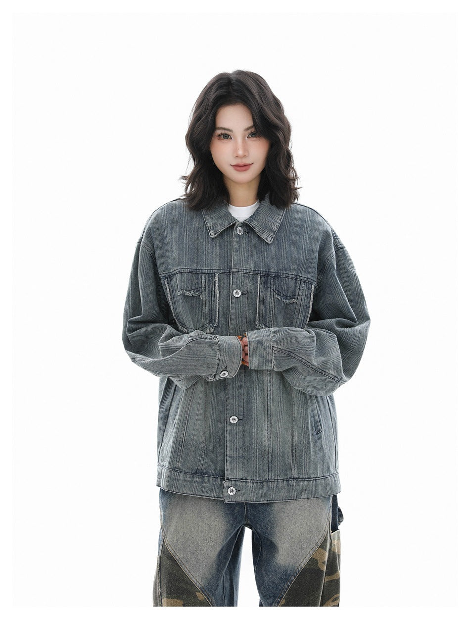 Model wearing a blue-gray oversized denim jacket with distressed chest pockets and loose patchwork jeans.