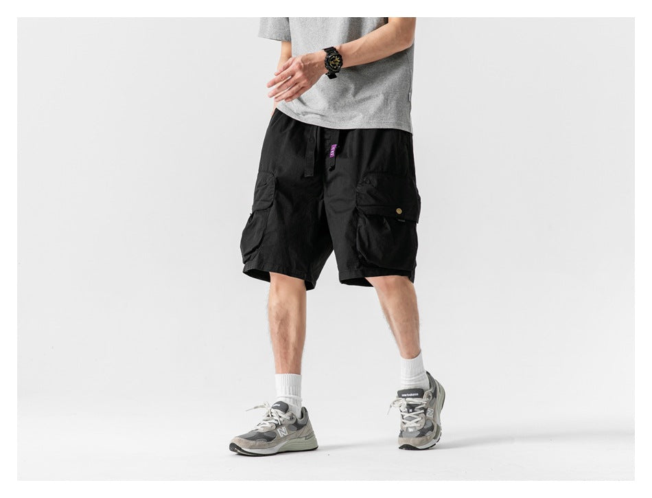 Front view of a model wearing black cargo shorts with large flap pockets.