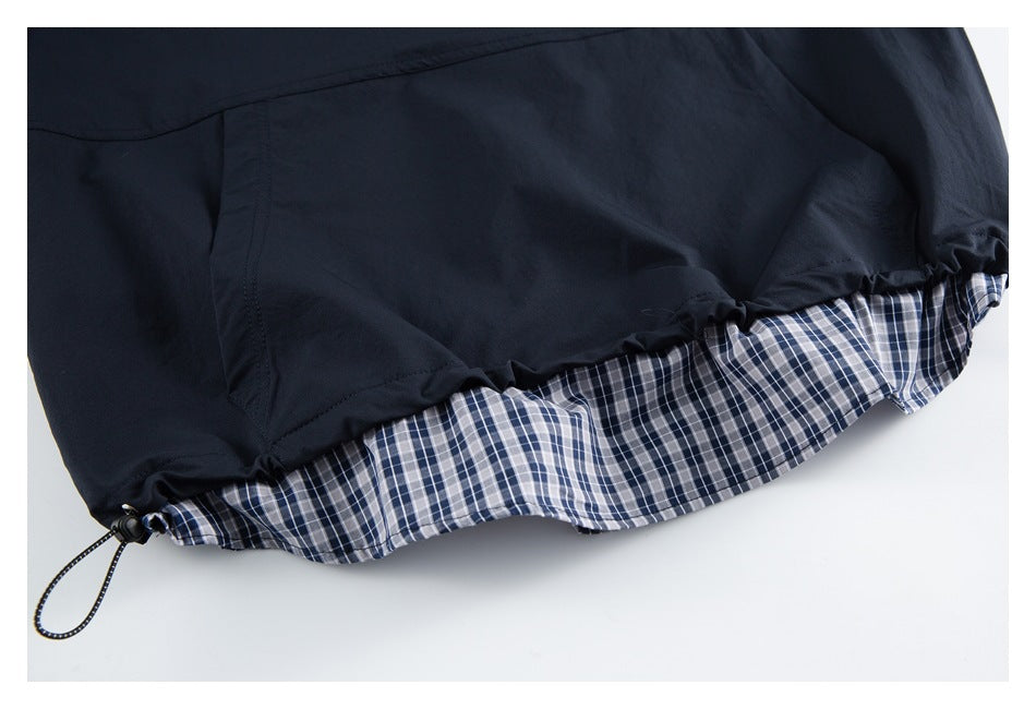 Close-up of a navy garment hem with a plaid lining and an adjustable drawcord.