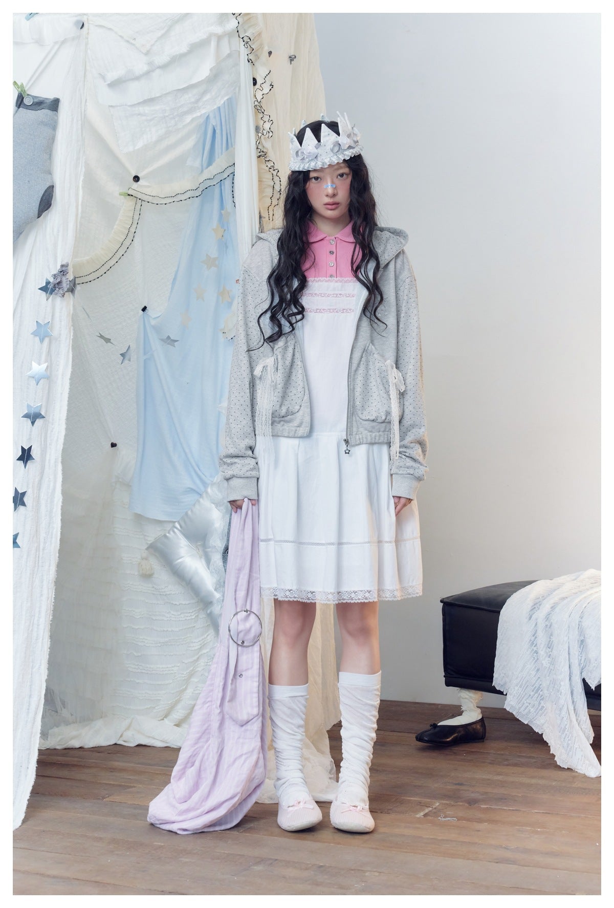 Model wearing the gray polka-dot zip hoodie with lace bow pockets over a white dress and pink polo
