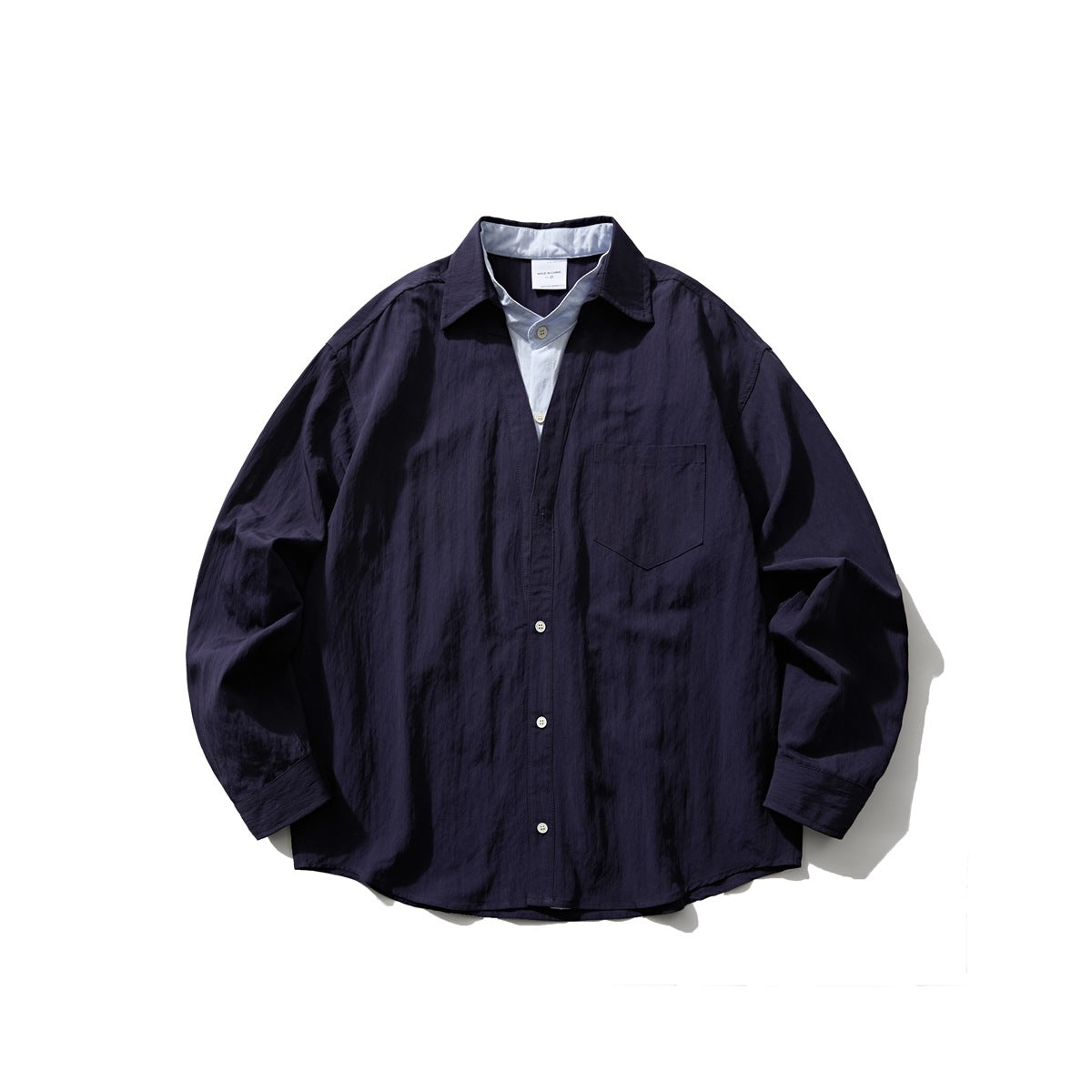 Dark navy long-sleeve button shirt with light blue layered placket and collar insert, flat lay front view