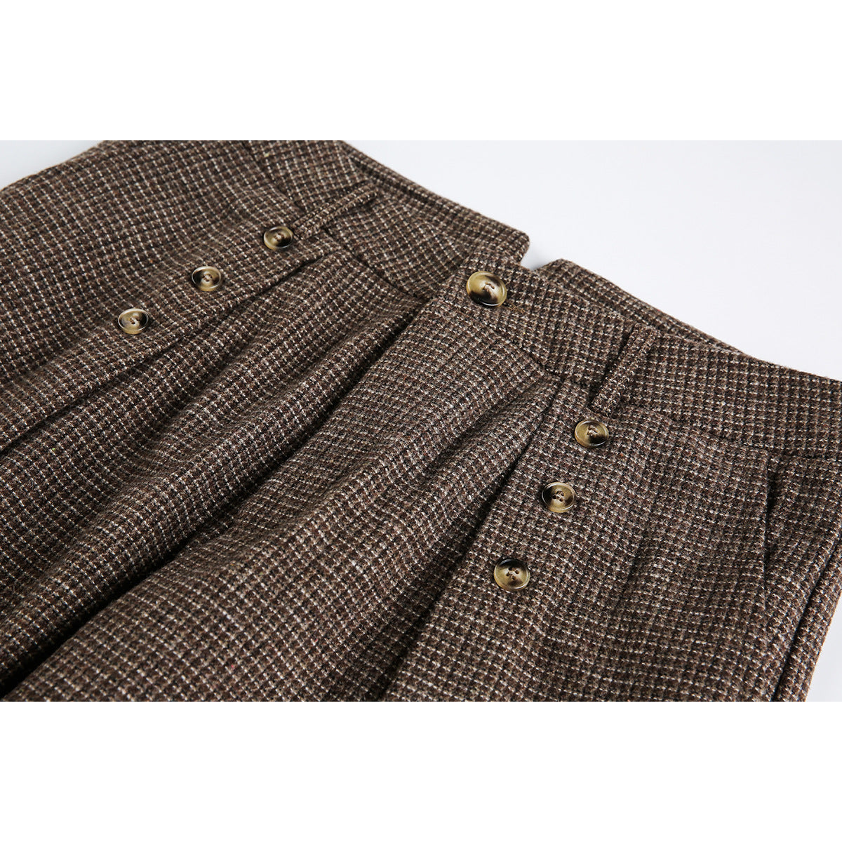 Close-up of brown small-check trousers showing the waistband, front pleats and brass-tone buttons.