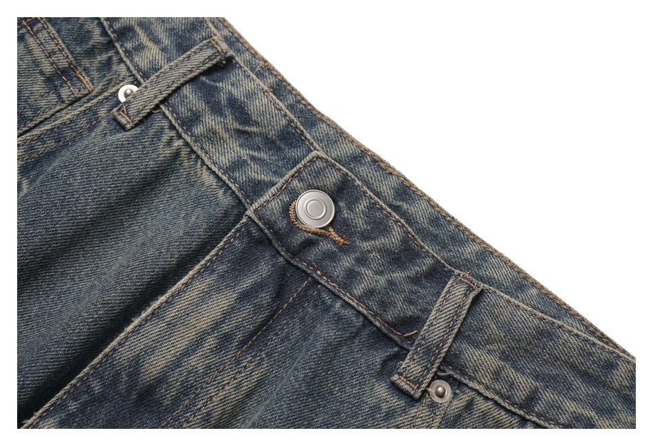 Close-up of the metal button, fly, and belt loops on faded dark blue jeans.