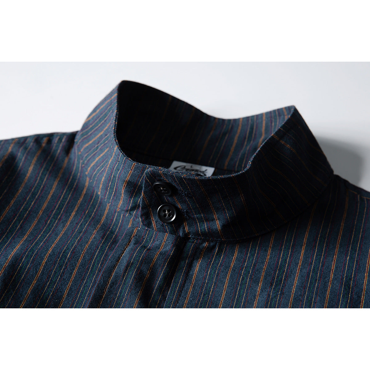 Close-up of a dark blue striped jacket collar with two black buttons and a stand collar.