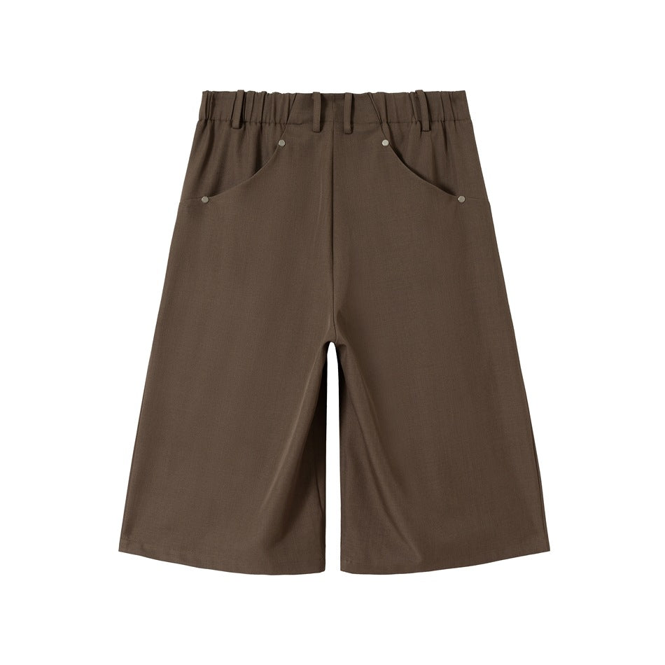 Front view of brown wide-leg shorts with an elasticized waistband, belt loops and curved rivet-trimmed pockets.