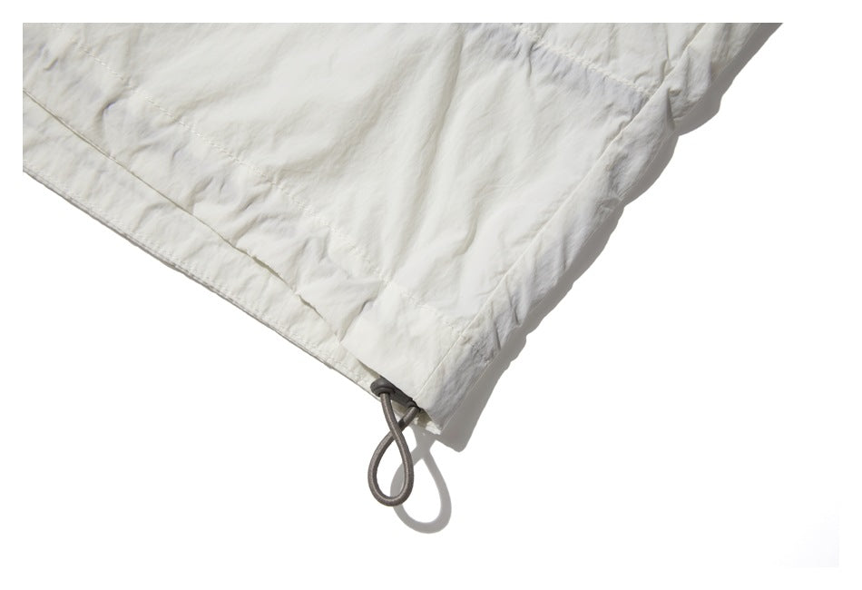 Close-up of an off-white garment hem with a gray loop drawcord.