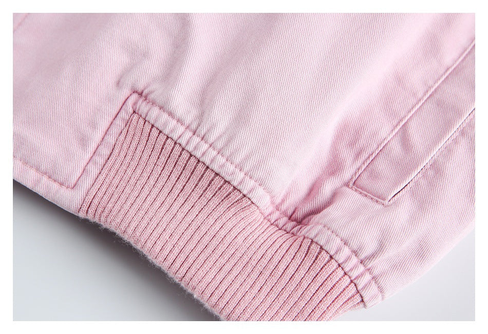 Close-up of a pale pink jacket's ribbed hem and nearby side pocket opening.