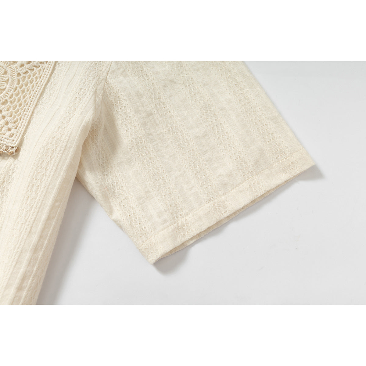 Close-up of the short sleeve and textured fabric of an ivory shirt.