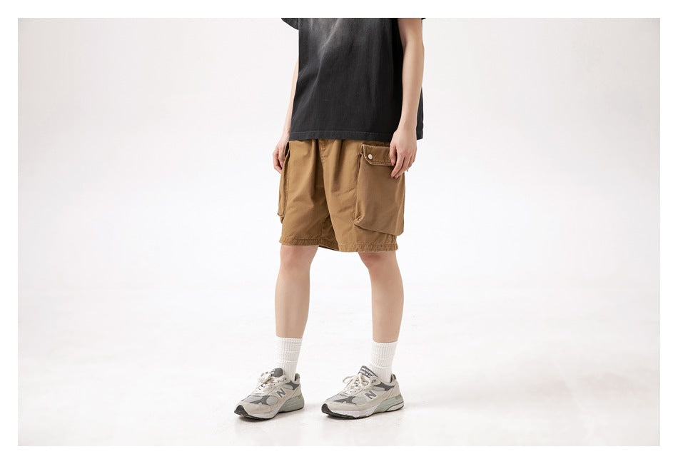 Three-quarter view of a model wearing brown cargo shorts with snap-flap pockets and a black T-shirt.