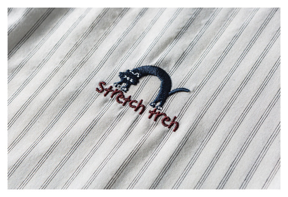 Embroidered navy and red lettering on cream fabric with fine dark stripes, shown close up.