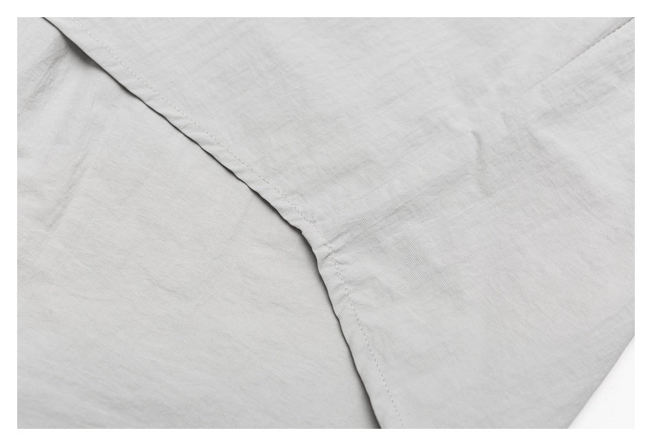 Close-up of a curved stitched seam on light gray fabric.