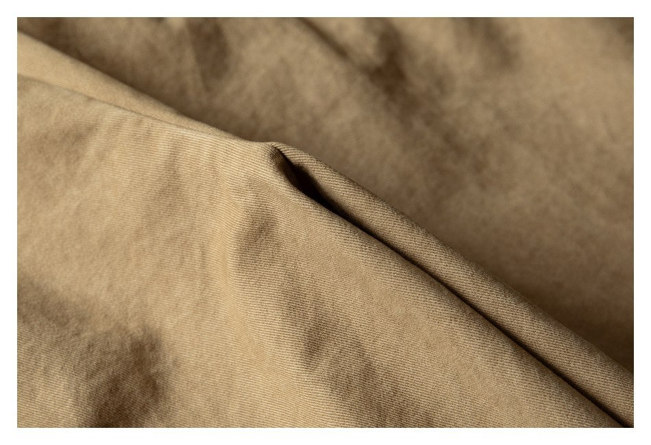 Macro view of tan garment fabric and a folded stitched edge.