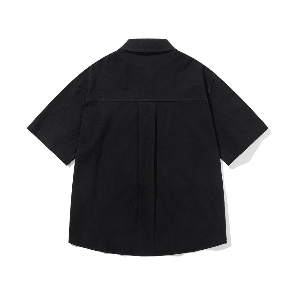 Back view of a black short-sleeve button-up shirt with a center pleat and curved hem.