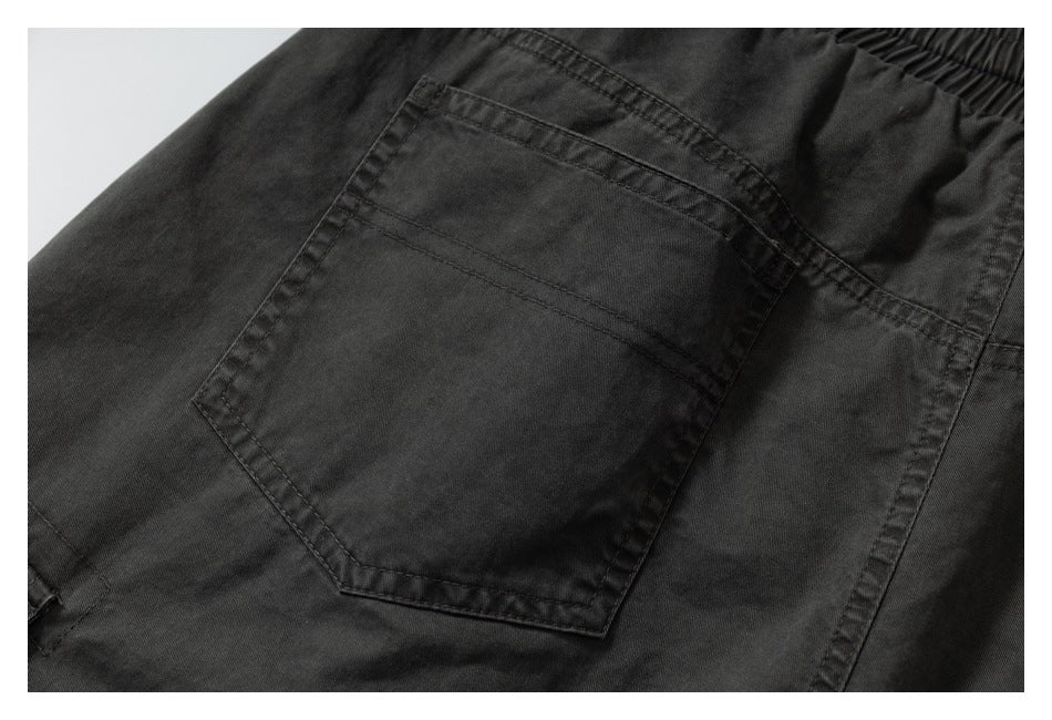 Close-up of a dark charcoal garment showing a stitched patch pocket and gathered waistband.